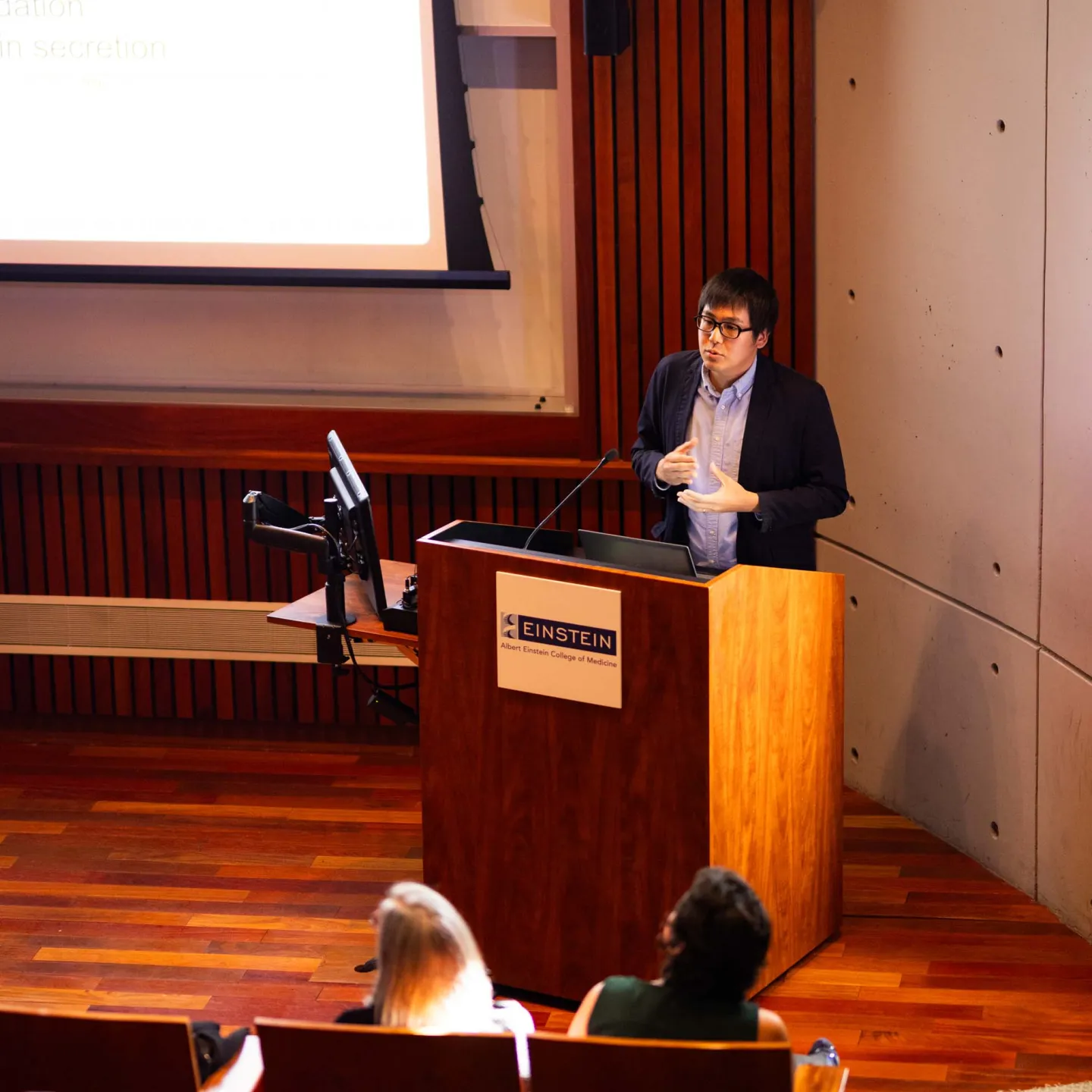 Junichi Okada presenting at podium 2 in Lefrak Auditorium