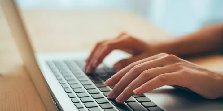 Hands typing on laptop keyboard