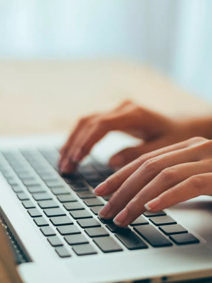 Hands typing on laptop keyboard