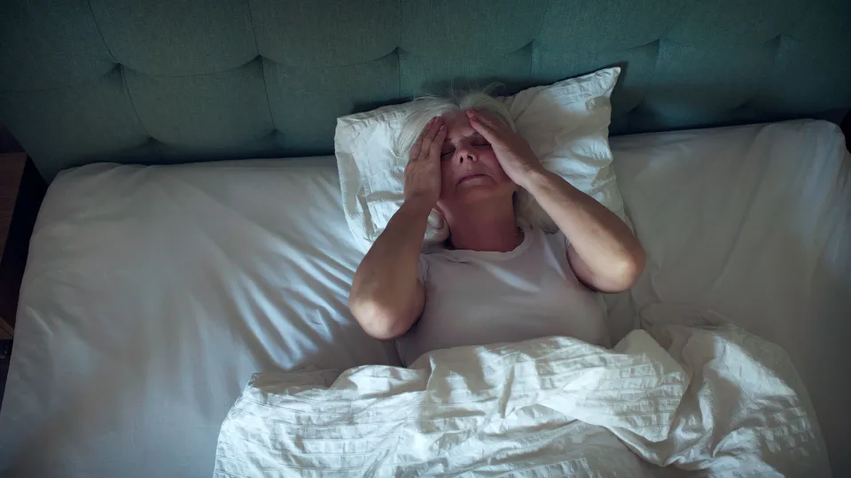 Anxious, mature woman trying to sleep at night. Dealing with sleeping disorder, head in hands